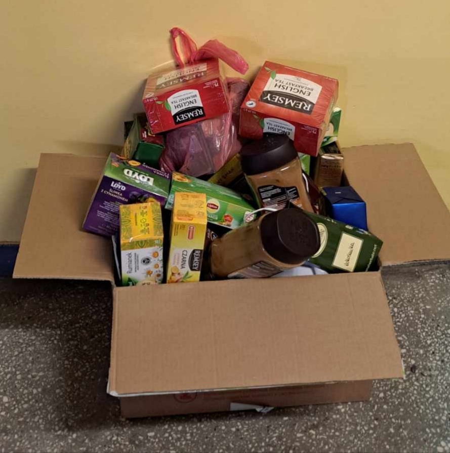 W szarym pudełku leżą pudełka różnych rodzajów herbat oraz kilka słoików kawy.