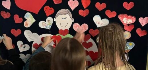 Dzieci przyczepiają  swoje czerwone serduszka do granatowej tablicy z napisem - Jestem życzliwy - serce rośnie…