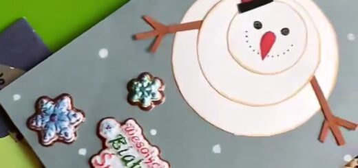 Wśród wielu kartek świątecznych leży szara karta z białym bałwanem i kolorowym napisem Wesołych świąt 