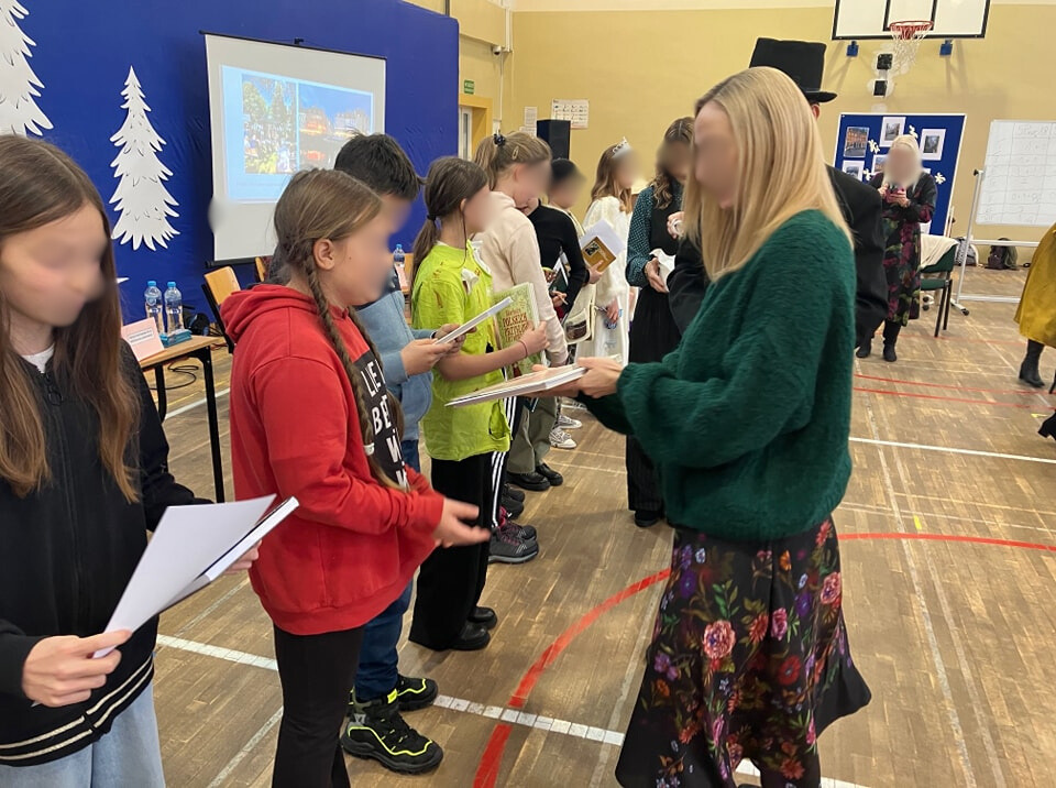 Na zdjęciu kobieta wręcza laureatom  dyplomy i nagrody za zajęcie czołowych miejsc w konkursie.