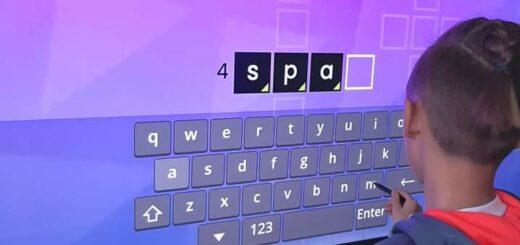 Uczeń stoi przed tablicą elektroniczna i rozwiązuje krzyżówkę.