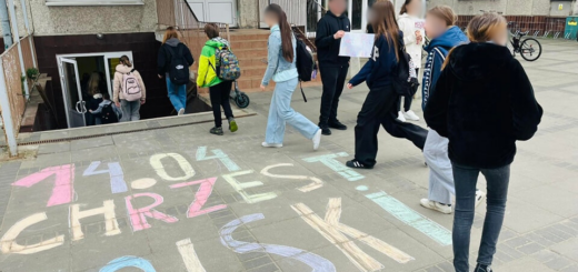 Przed budynkiem na chodniku widnieje napis  14.04 CHRZEST POLSKI, uczniowie wchodzą do budynku