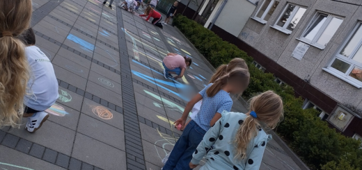 Dzieci rysują kredą  na chodniku przed szkołą.