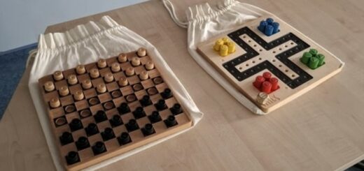 Na stole leżą gry planszówki dla niewidomych warcaby i chińczyk