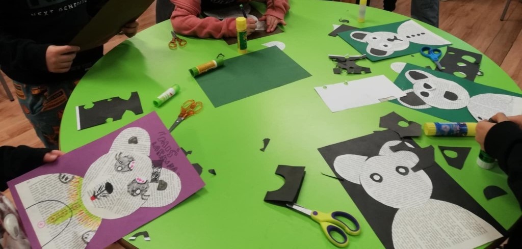 Na zielonym stole leżą prace plastyczne dzieci - misie wycięte z pożółkłych starych zniszczonych książek.