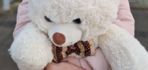 Wielki biały miś w objęciach dziecka.