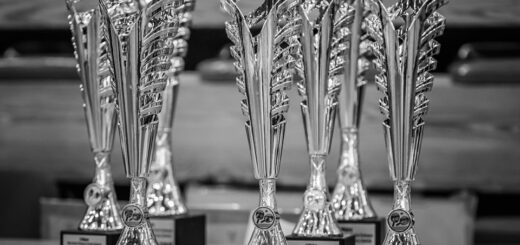 Na czarnobiałym zdjęciu stoi 7 pucharów , nagród w Mistrzostwach Olsztyna w Tenisie Stołowym